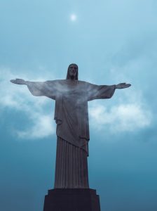 a statue of a person holding the arms out with Christ the Redeemer in the background